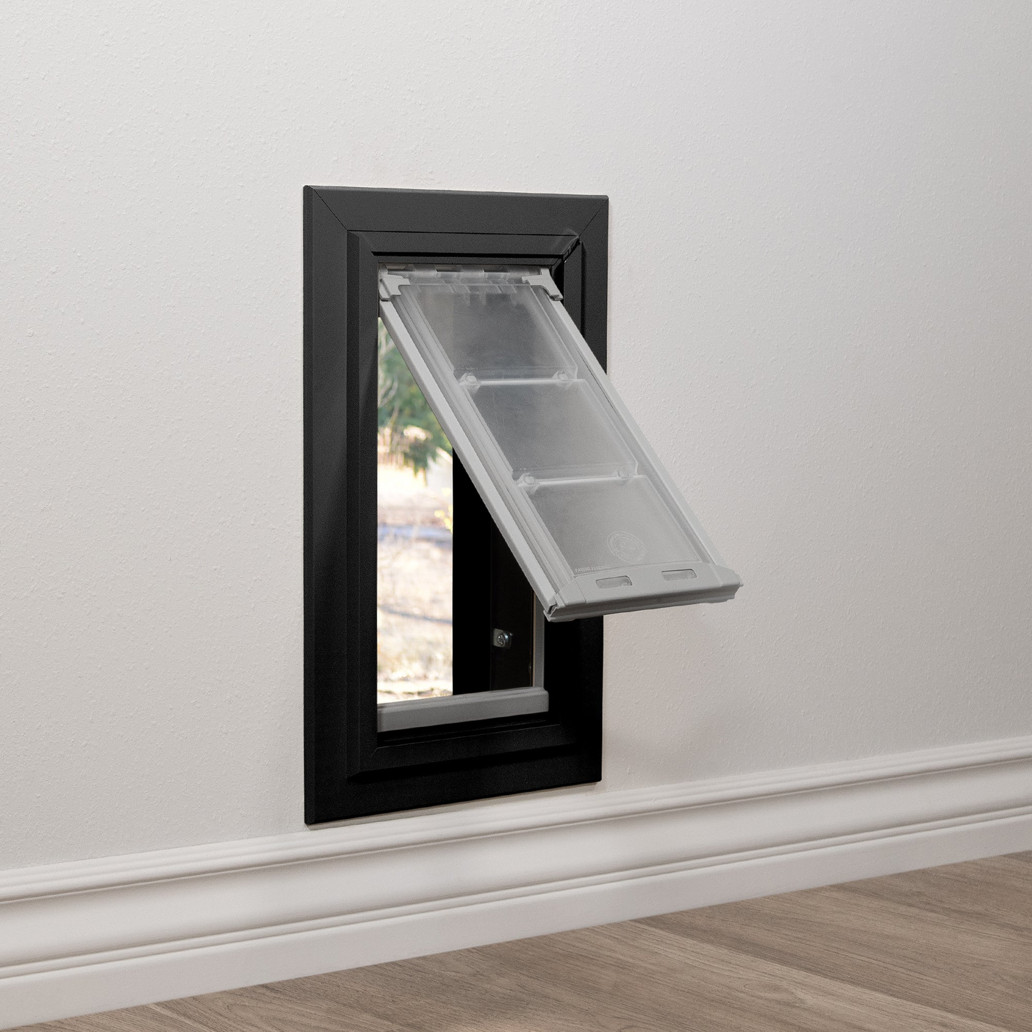 Installed black Endura Flap dog door for walls, shown with the flap open for pet access. This illustrates the convenience of a through wall dog door.