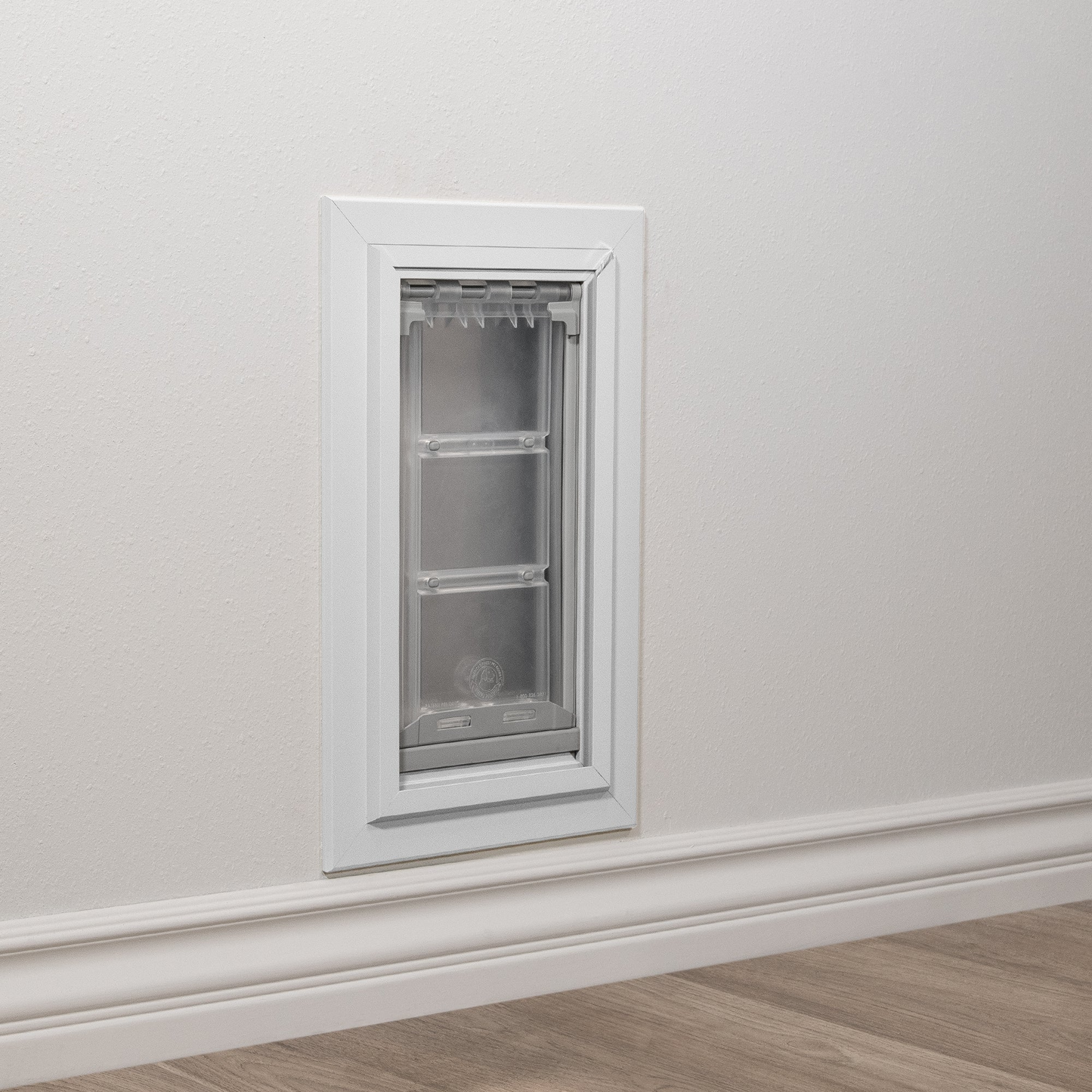 Installed white Endura Flap pet door for wall, flush against an exterior wall. This is a prime example of a secure and energy-efficient wall entry pet door.