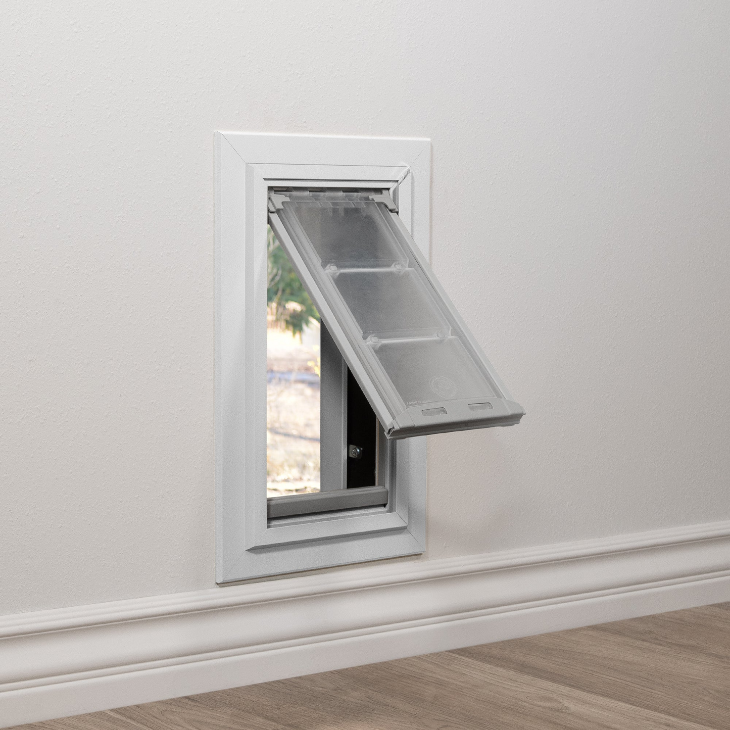 Installed view of a white Endura Flap dog door for walls, shown with the flap open. This illustrates how easily pets can use these through wall dog doors.