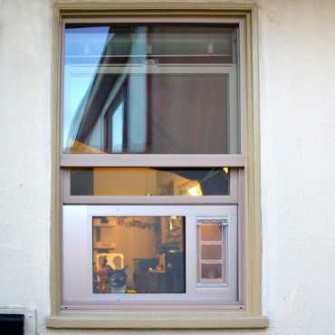 A double-hung window with a visible reflection of an interior room.