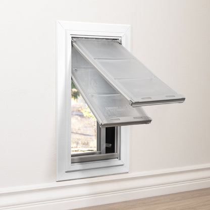 A pet door with transparent flaps is installed in a wall.