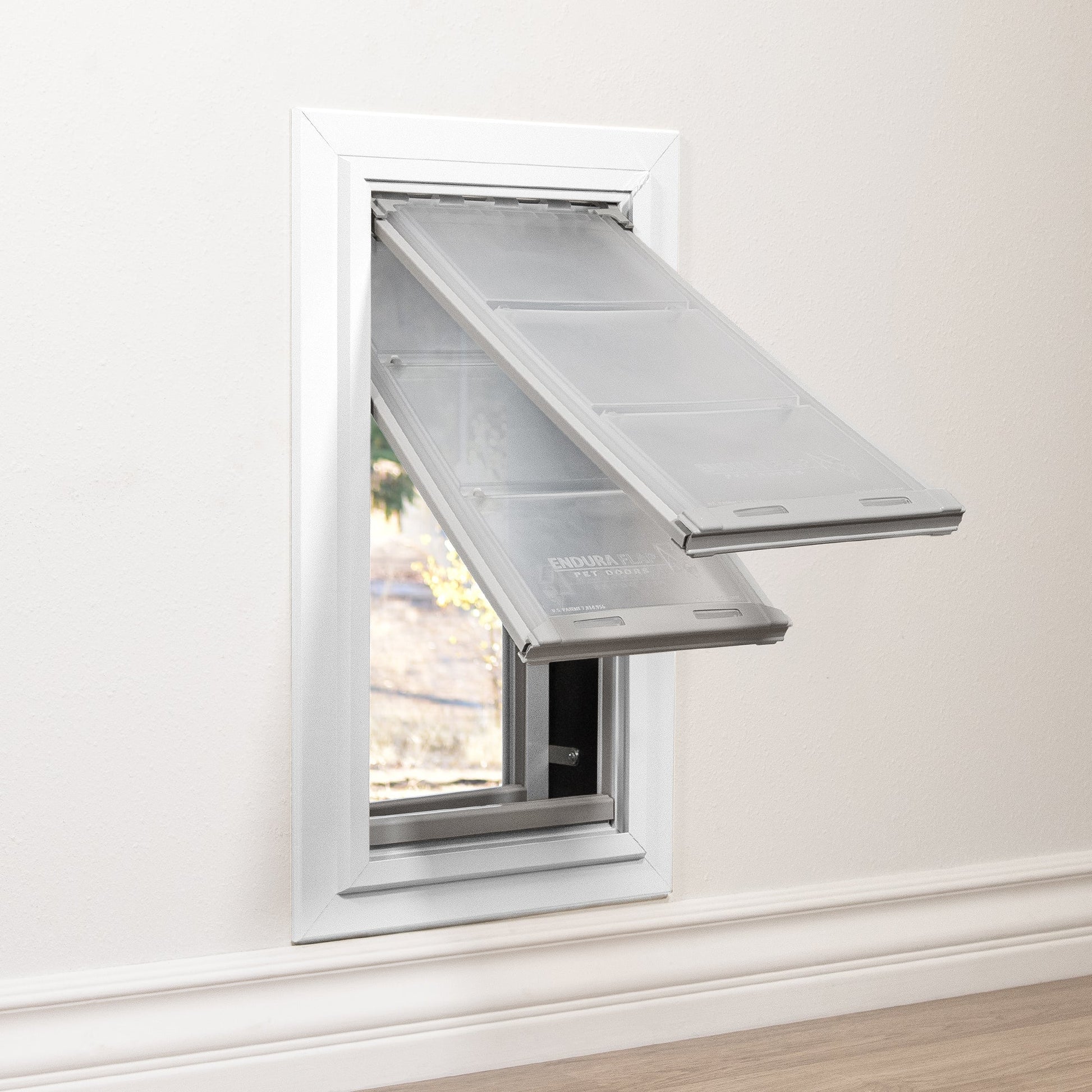 A pet door with two translucent flaps is installed in a wall.