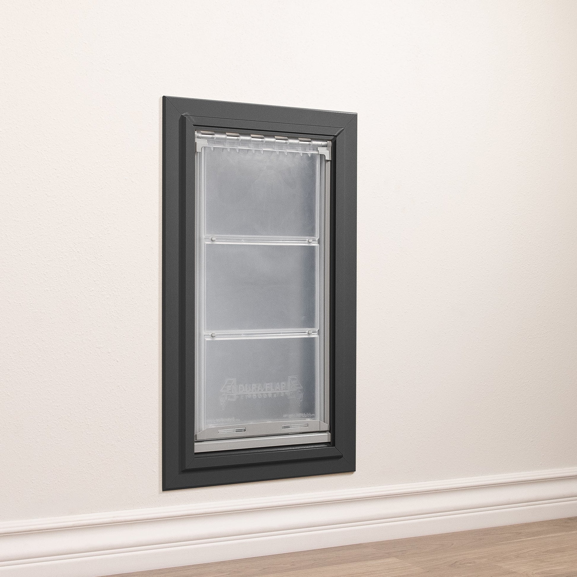 A DuraFlap pet door is installed in a white wall with white trim.