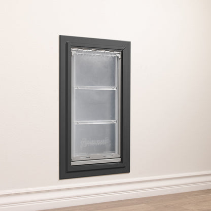 A DuraFlap pet door is installed in a white wall with white trim.