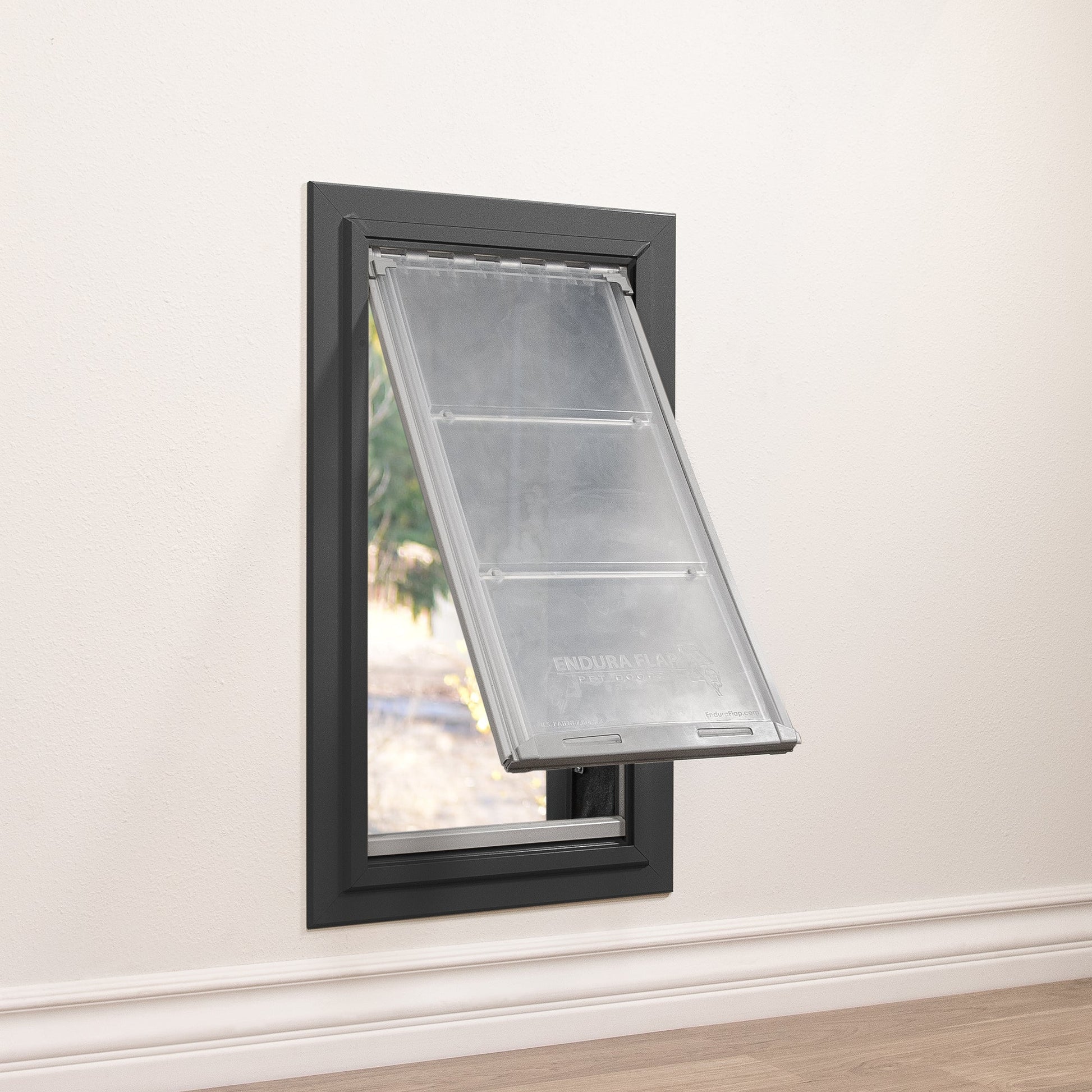 A black-framed dog door with a partially open "Endura Flap" in a white wall.