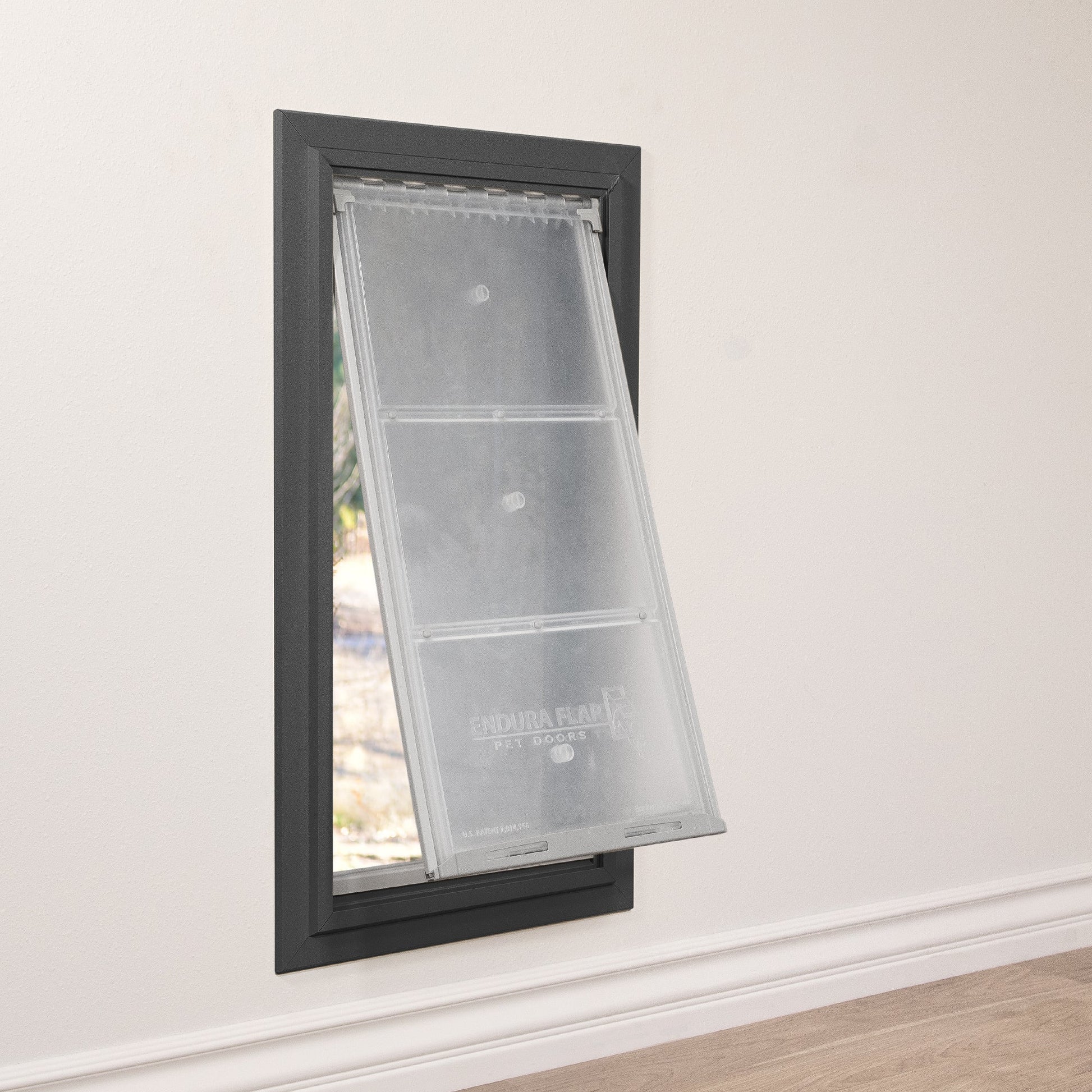 A pet door labeled "Endura Flap Pet Doors" is installed in a wall, with the flap partially open.